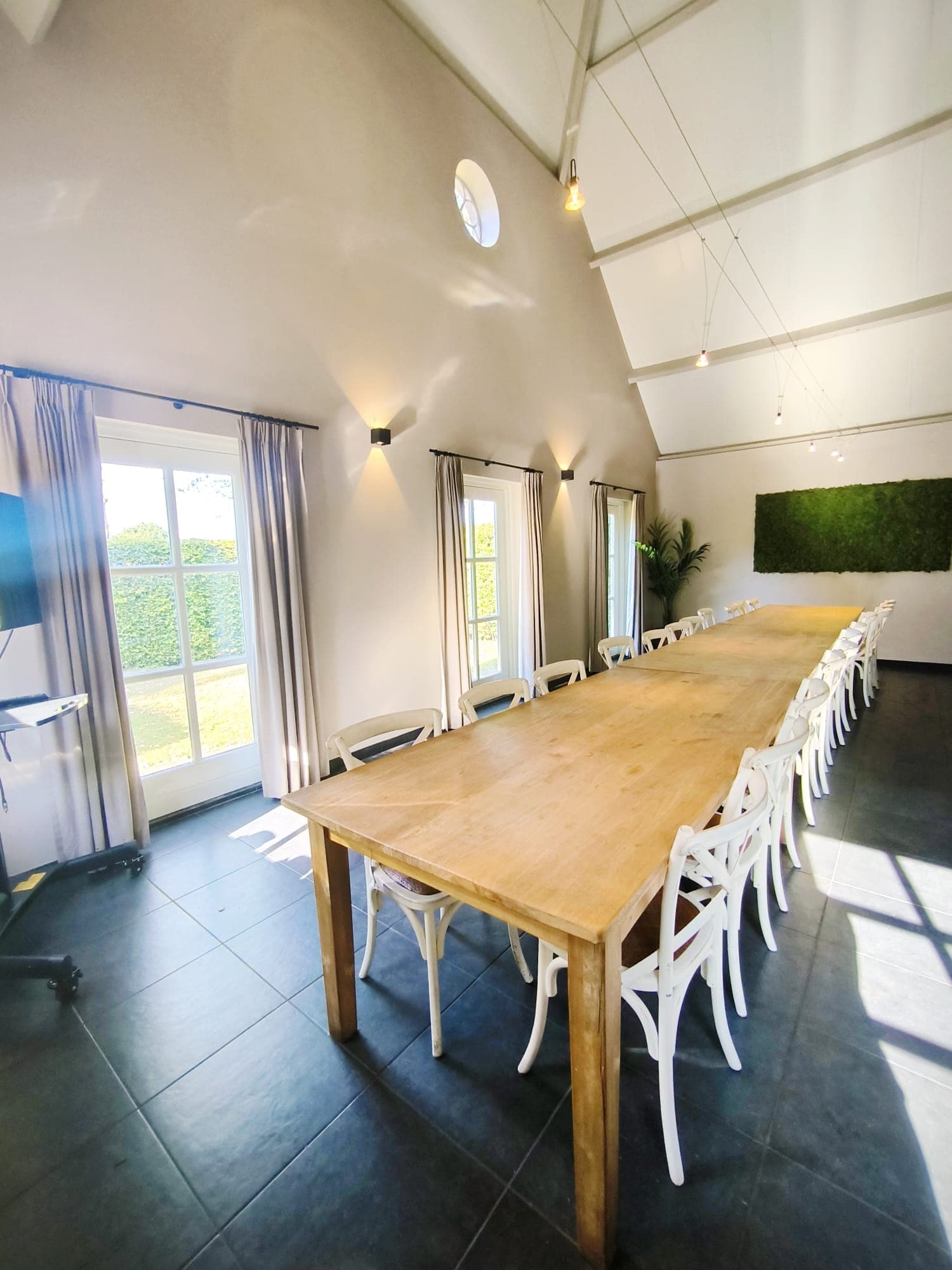 De lange tafel in de ruimte, met daglicht door de ramen